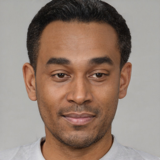 Joyful latino young-adult male with short  black hair and brown eyes