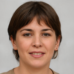 Joyful white young-adult female with medium  brown hair and grey eyes