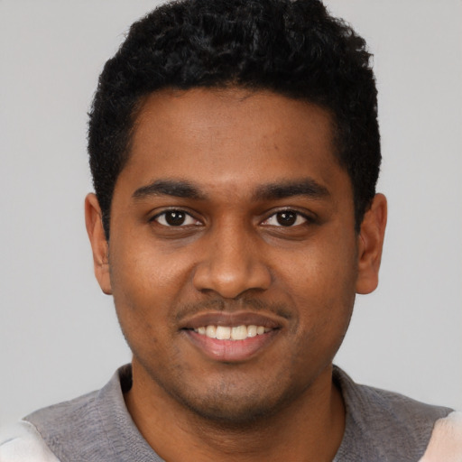 Joyful black young-adult male with short  black hair and brown eyes