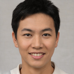 Joyful asian young-adult male with short  black hair and brown eyes