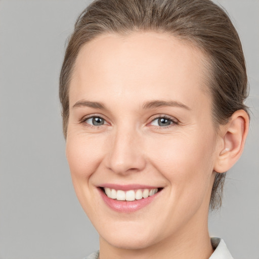 Joyful white young-adult female with medium  brown hair and grey eyes