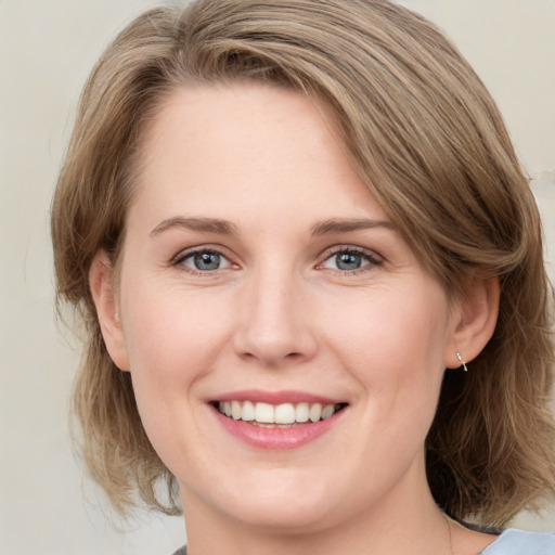 Joyful white young-adult female with medium  brown hair and grey eyes