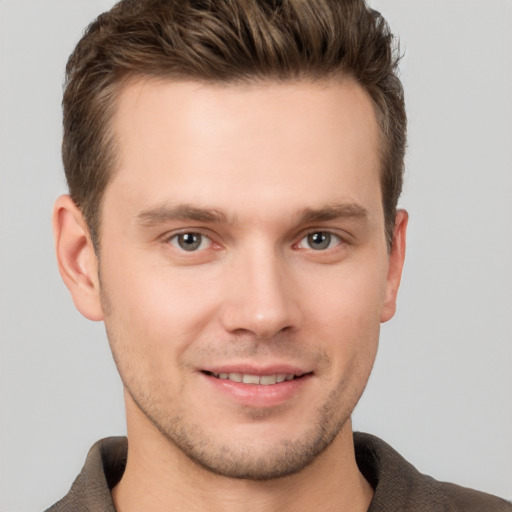 Joyful white young-adult male with short  brown hair and grey eyes