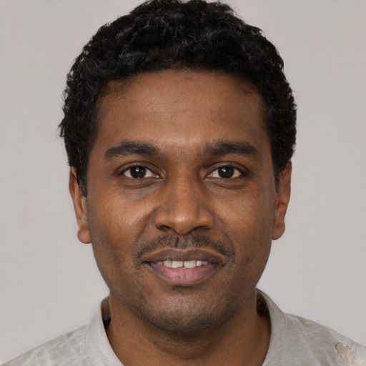 Joyful black young-adult male with short  black hair and brown eyes