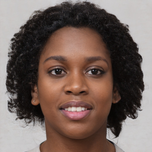 Joyful black young-adult female with long  black hair and brown eyes