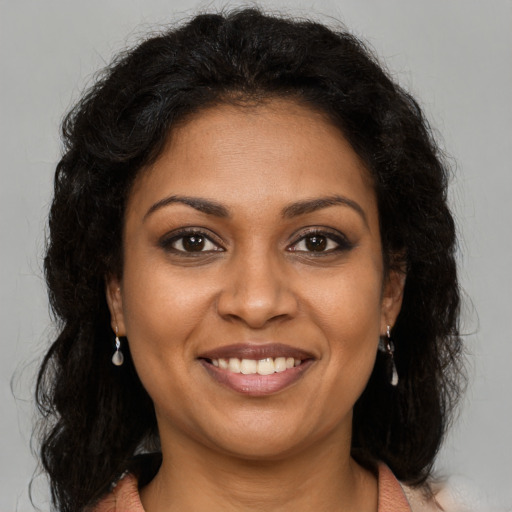 Joyful black young-adult female with long  brown hair and brown eyes