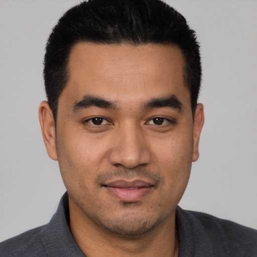Joyful latino young-adult male with short  black hair and brown eyes
