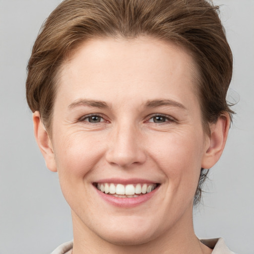 Joyful white young-adult female with short  brown hair and grey eyes