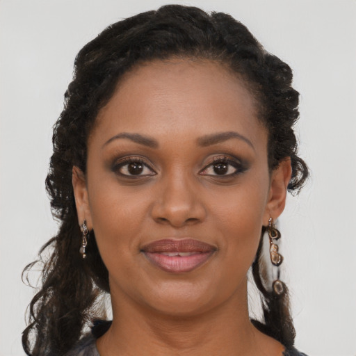 Joyful black young-adult female with long  brown hair and brown eyes