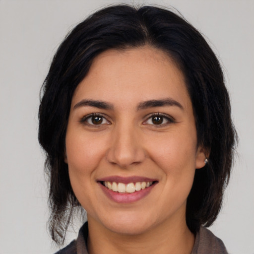 Joyful latino young-adult female with medium  brown hair and brown eyes