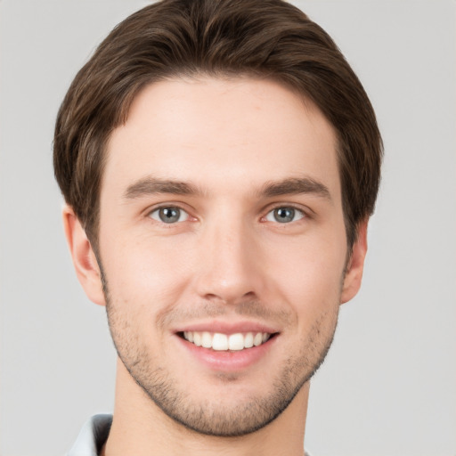 Joyful white young-adult male with short  brown hair and grey eyes