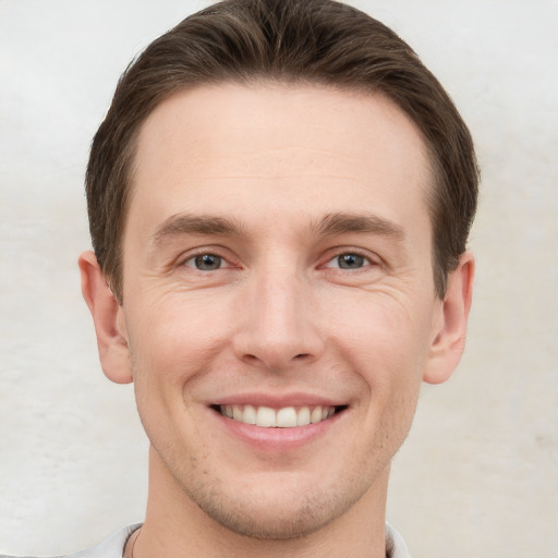 Joyful white young-adult male with short  brown hair and grey eyes