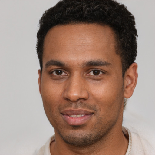 Joyful black young-adult male with short  brown hair and brown eyes