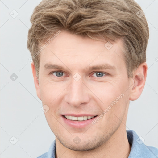 Joyful white young-adult male with short  brown hair and grey eyes