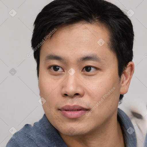 Joyful asian young-adult male with short  brown hair and brown eyes