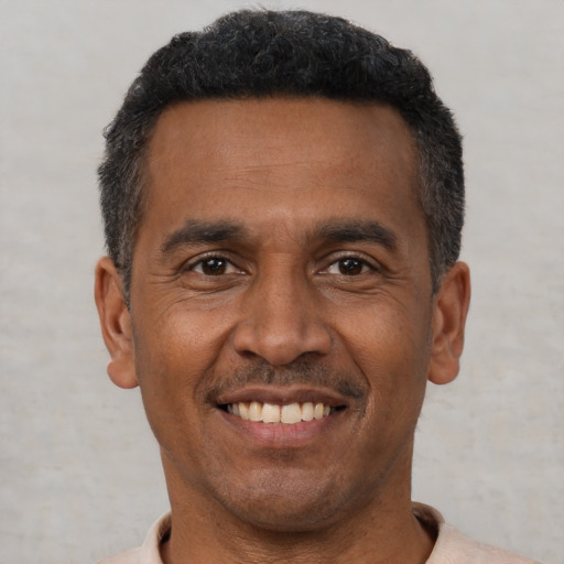 Joyful black adult male with short  black hair and brown eyes