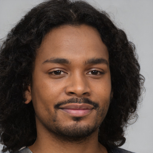 Joyful black young-adult male with long  brown hair and brown eyes