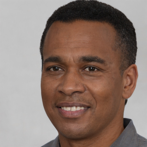 Joyful black adult male with short  black hair and brown eyes