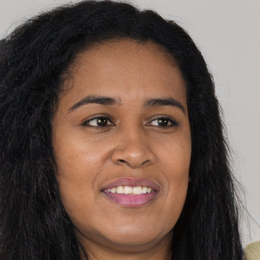 Joyful black young-adult female with long  brown hair and brown eyes