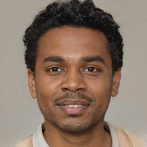 Joyful black young-adult male with short  black hair and brown eyes