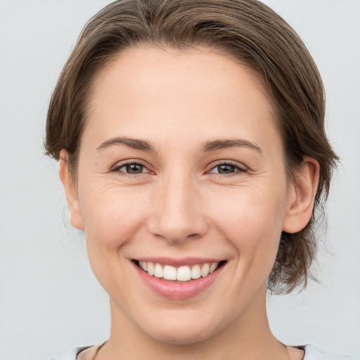 Joyful white young-adult female with medium  brown hair and grey eyes