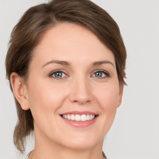 Joyful white young-adult female with medium  brown hair and grey eyes