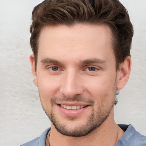 Joyful white young-adult male with short  brown hair and grey eyes