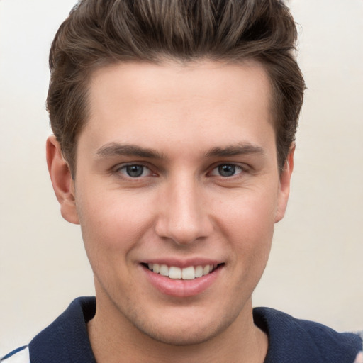 Joyful white young-adult male with short  brown hair and grey eyes