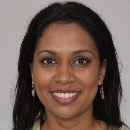 Joyful black young-adult female with long  brown hair and brown eyes