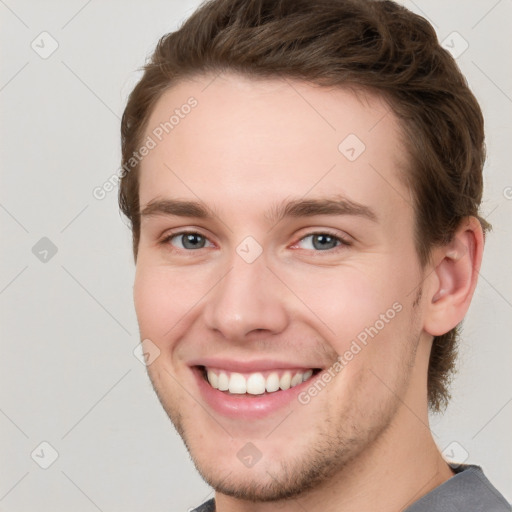 Joyful white young-adult male with short  brown hair and grey eyes