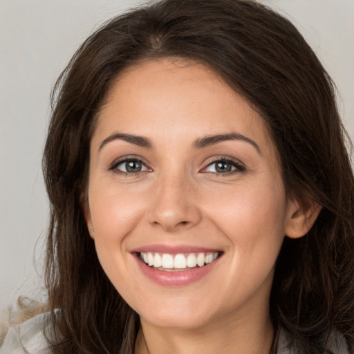 Joyful white young-adult female with long  brown hair and brown eyes