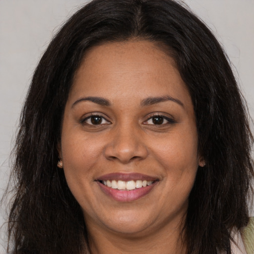 Joyful black young-adult female with long  brown hair and brown eyes