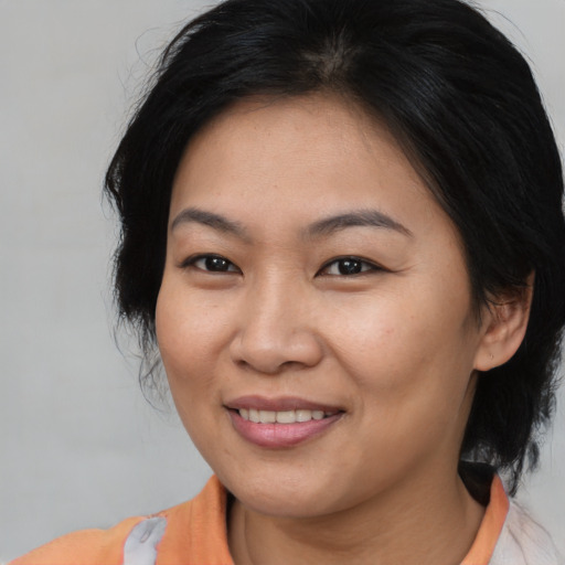 Joyful asian adult female with medium  brown hair and brown eyes