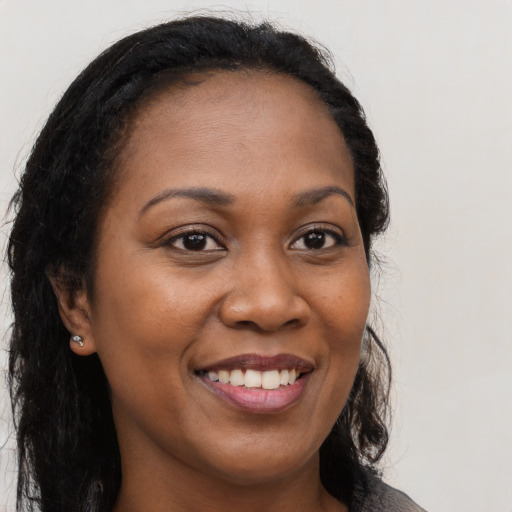 Joyful black young-adult female with long  brown hair and brown eyes