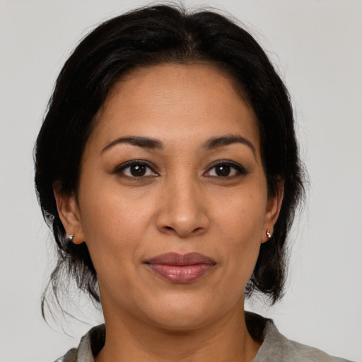 Joyful latino adult female with medium  brown hair and brown eyes