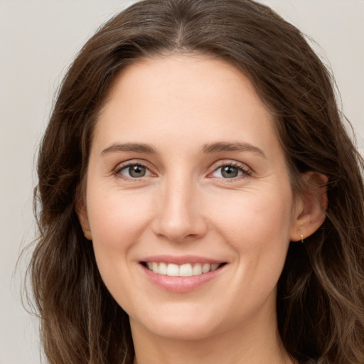 Joyful white young-adult female with long  brown hair and grey eyes