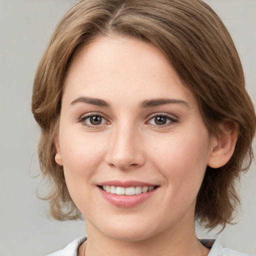 Joyful white young-adult female with medium  brown hair and grey eyes