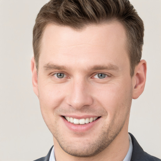 Joyful white young-adult male with short  brown hair and grey eyes