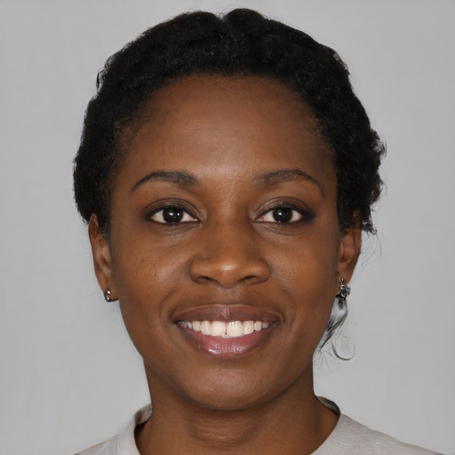 Joyful black young-adult female with short  black hair and brown eyes