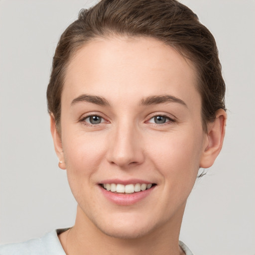 Joyful white young-adult female with short  brown hair and grey eyes