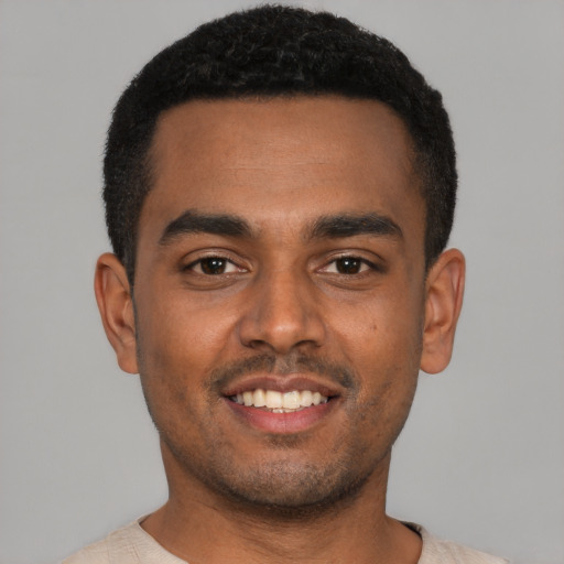 Joyful black young-adult male with short  black hair and brown eyes