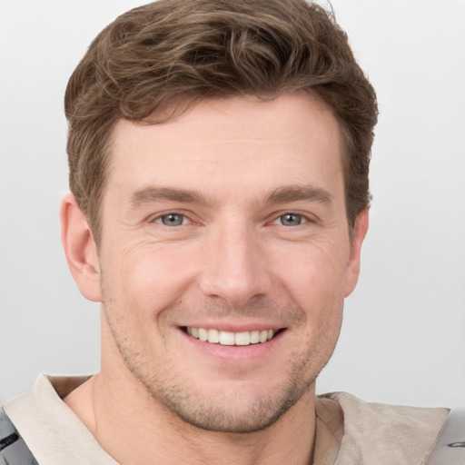 Joyful white young-adult male with short  brown hair and grey eyes