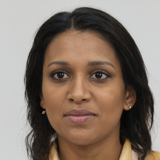 Joyful black young-adult female with long  brown hair and brown eyes