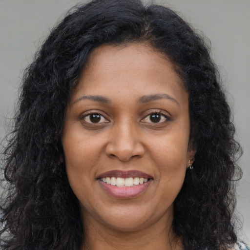 Joyful black young-adult female with long  brown hair and brown eyes