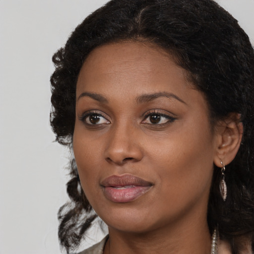 Joyful black young-adult female with long  brown hair and brown eyes