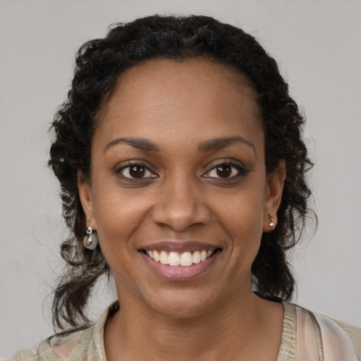 Joyful black young-adult female with long  brown hair and brown eyes