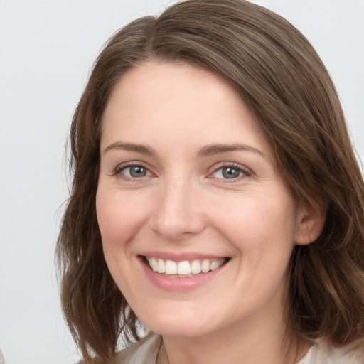 Joyful white young-adult female with medium  brown hair and grey eyes