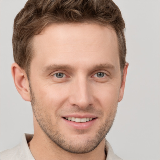 Joyful white young-adult male with short  brown hair and grey eyes