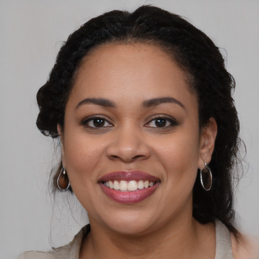 Joyful black young-adult female with long  black hair and brown eyes