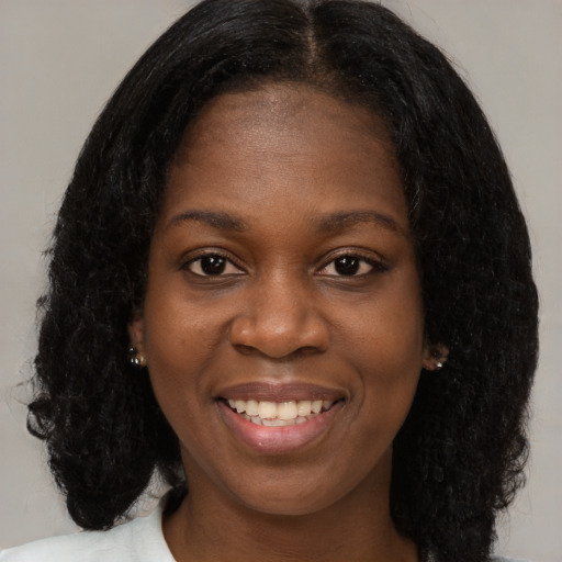 Joyful black young-adult female with long  brown hair and brown eyes